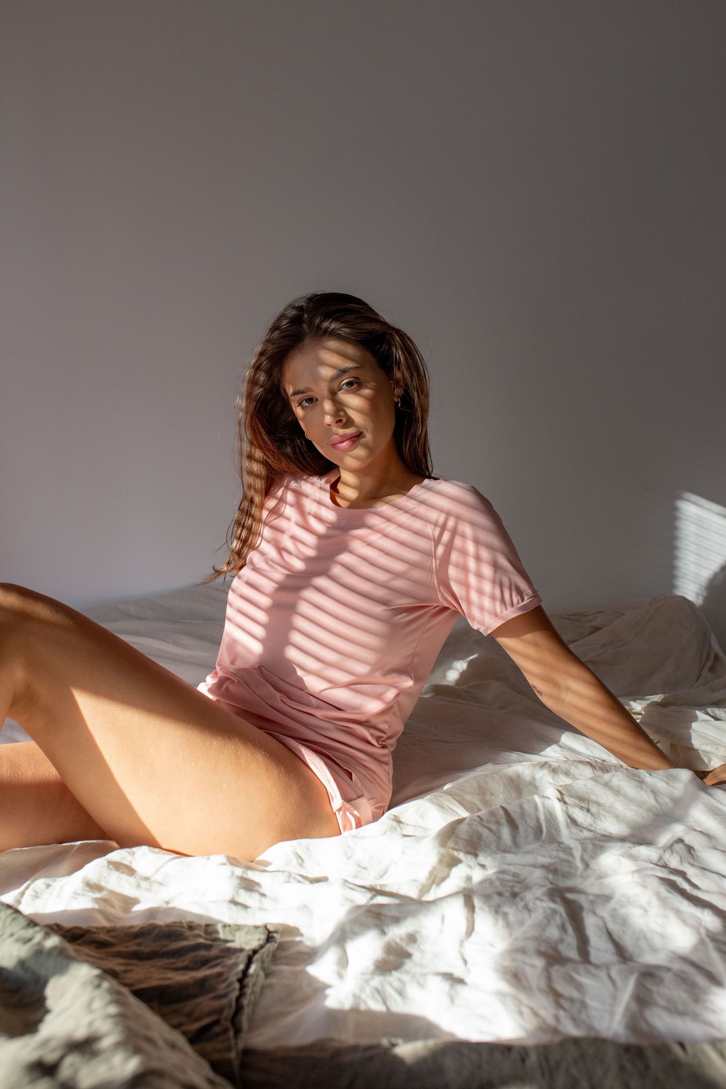 modelka w różowej piżamie siedząca na łóżku