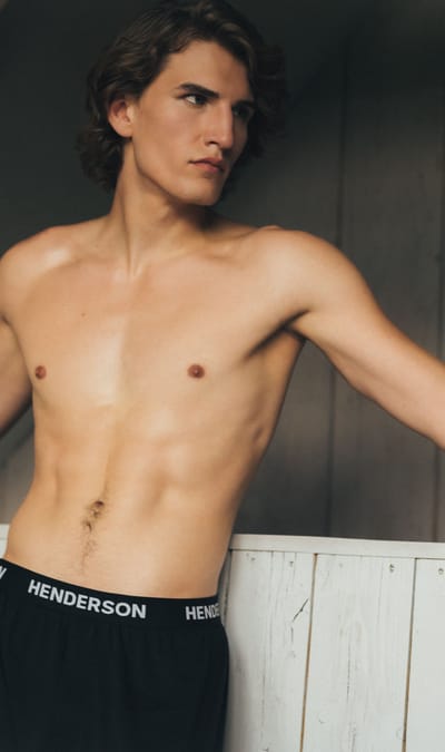 mężczyzna w czarnych bokserkach na tle drewnianej ściany ESOTIQ